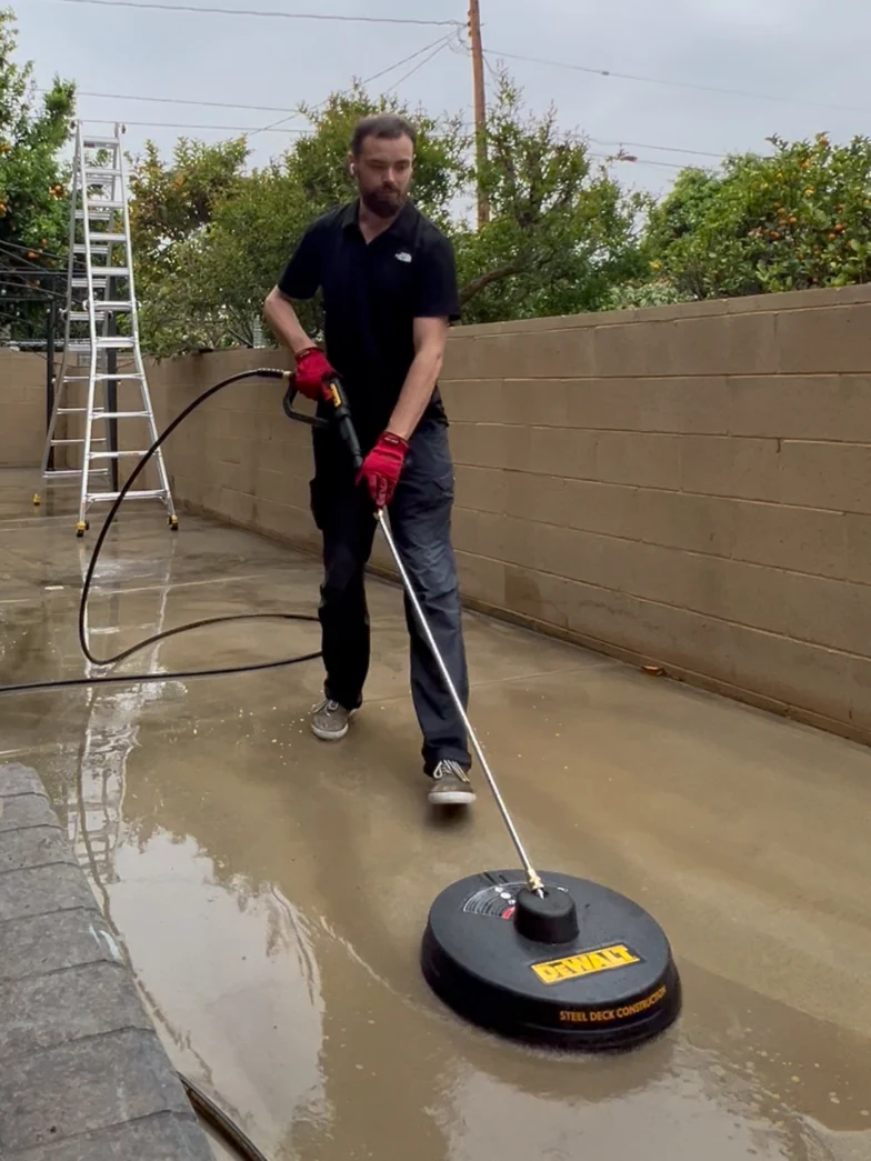 Technician pressure-washing a driveway with a surface-cleaner attachment